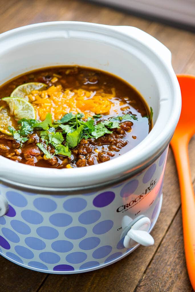 taco soup with cilantro, cheese and lime wedge in polka dot slow cooker