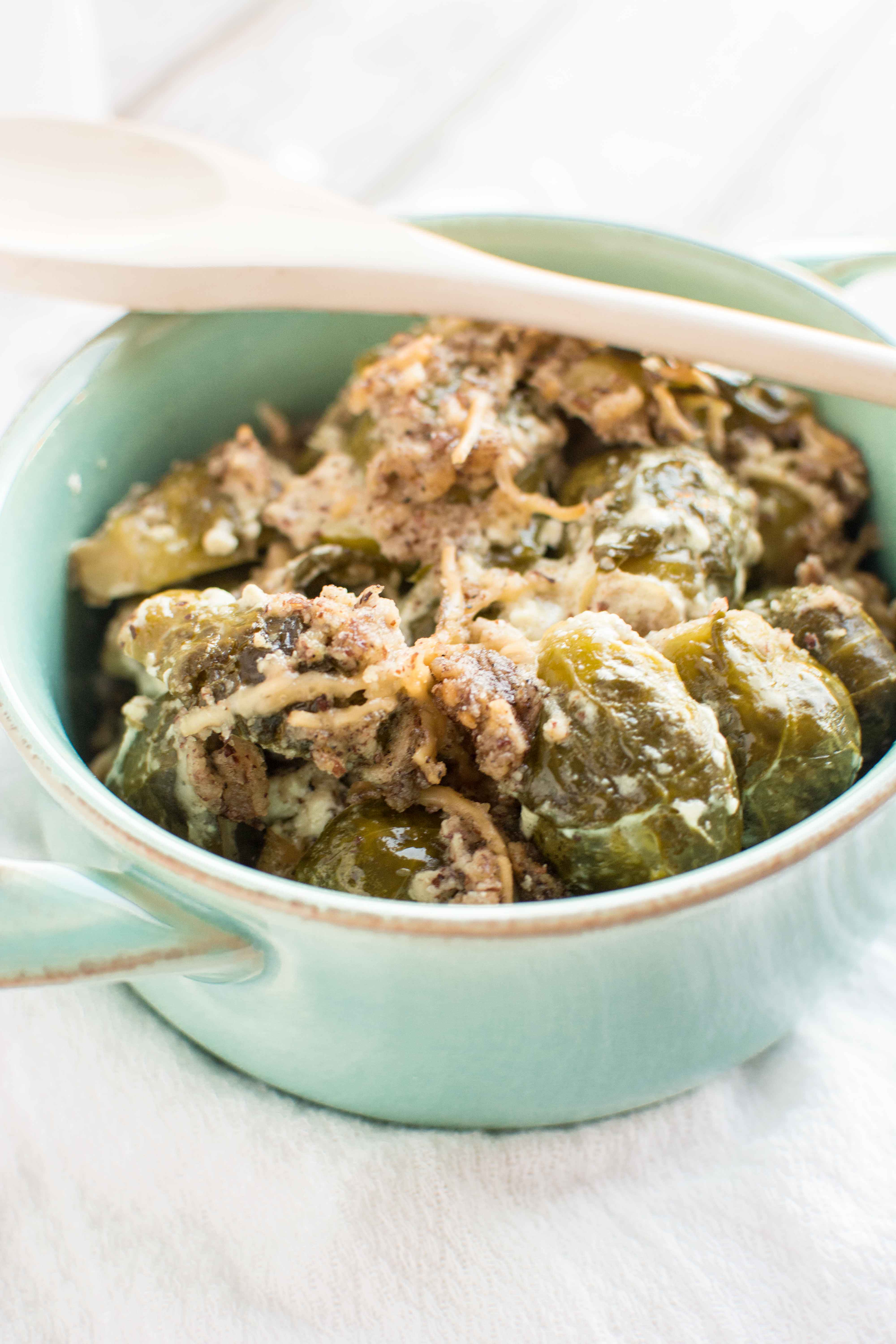 brussels sprouts in green bowl with wooden spoon across bowl