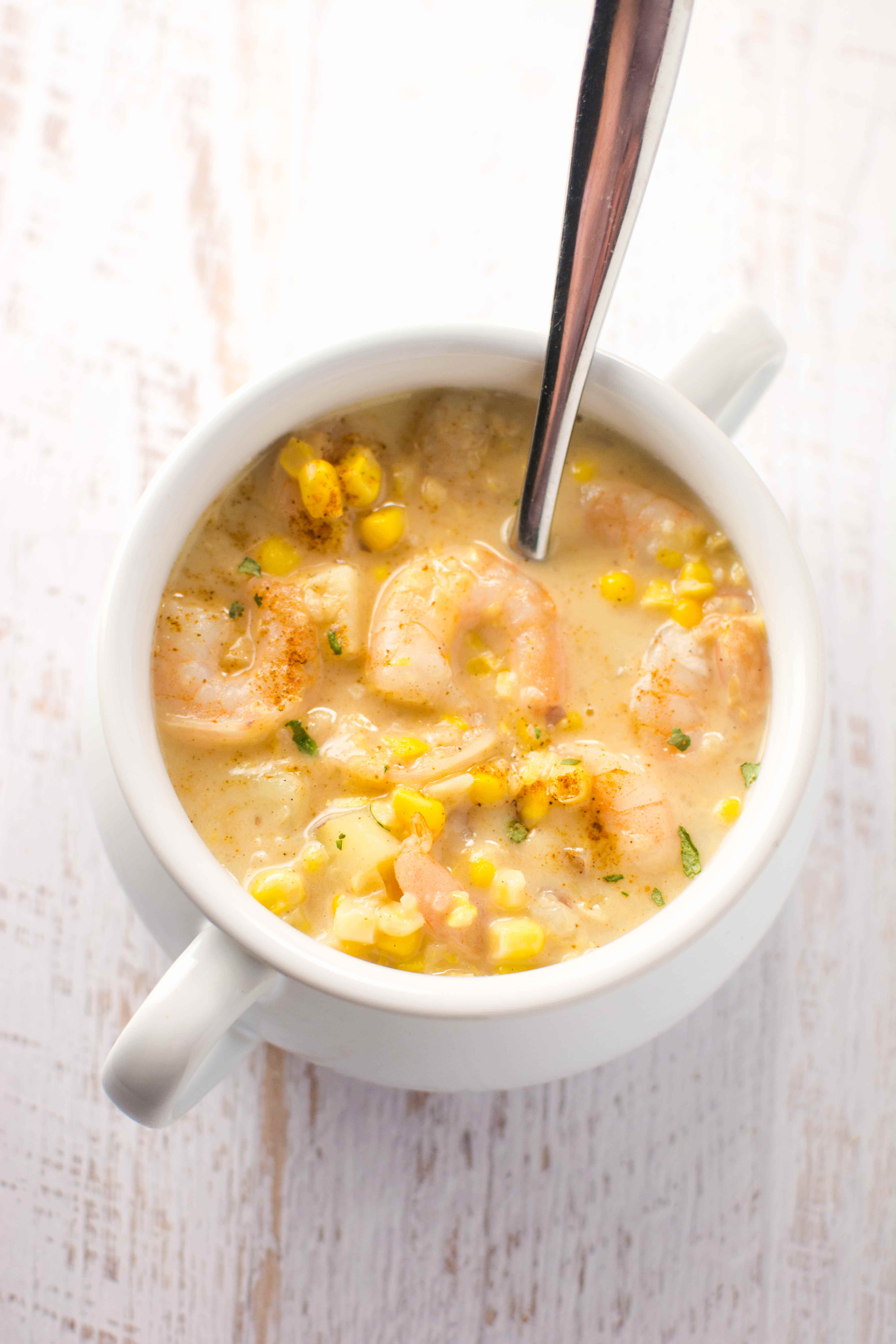 white bowl and spoon filled with cajun corn and shrimp chowder