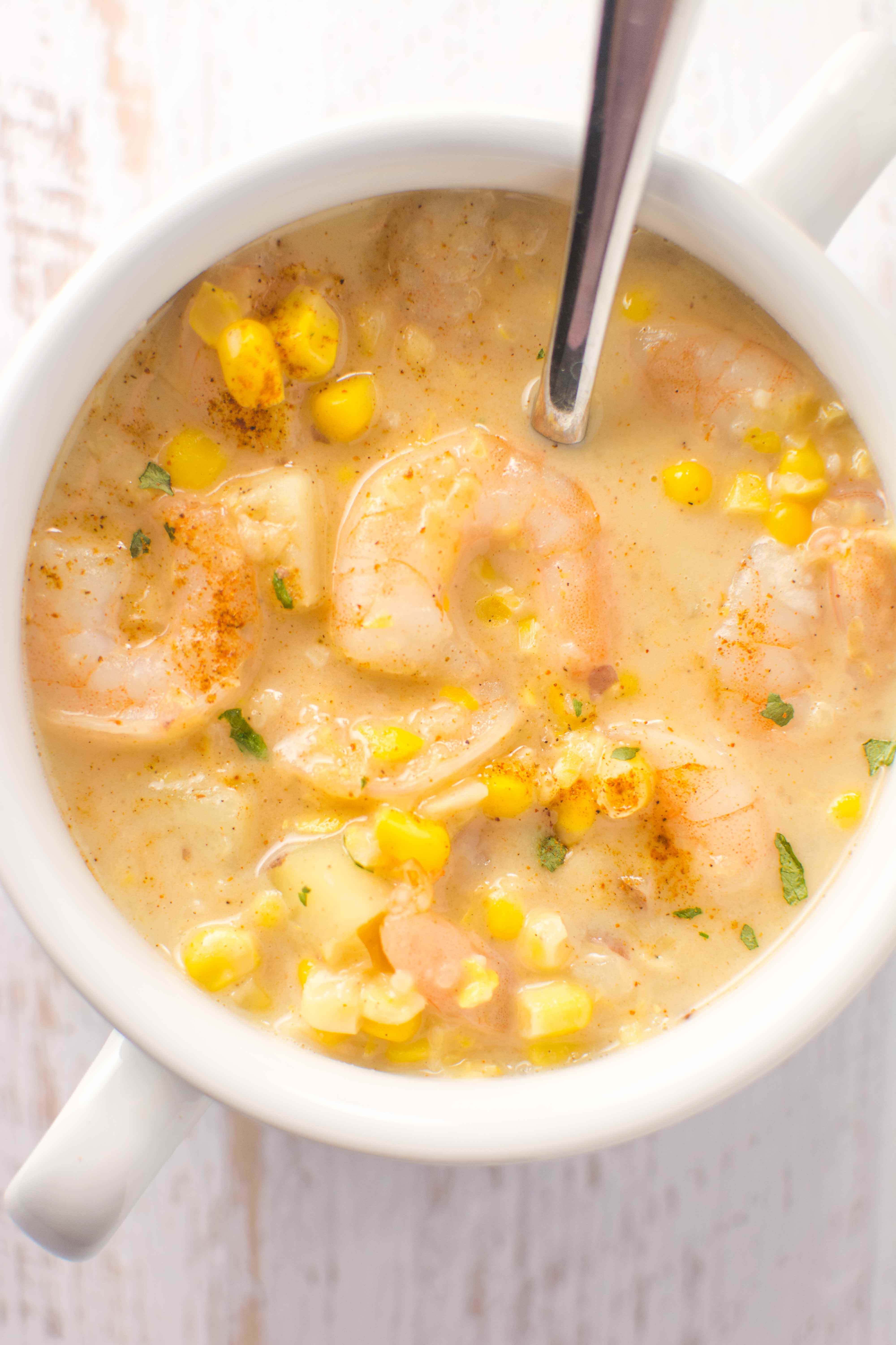 white bowl and spoon filled with cajun corn and shrimp chowder