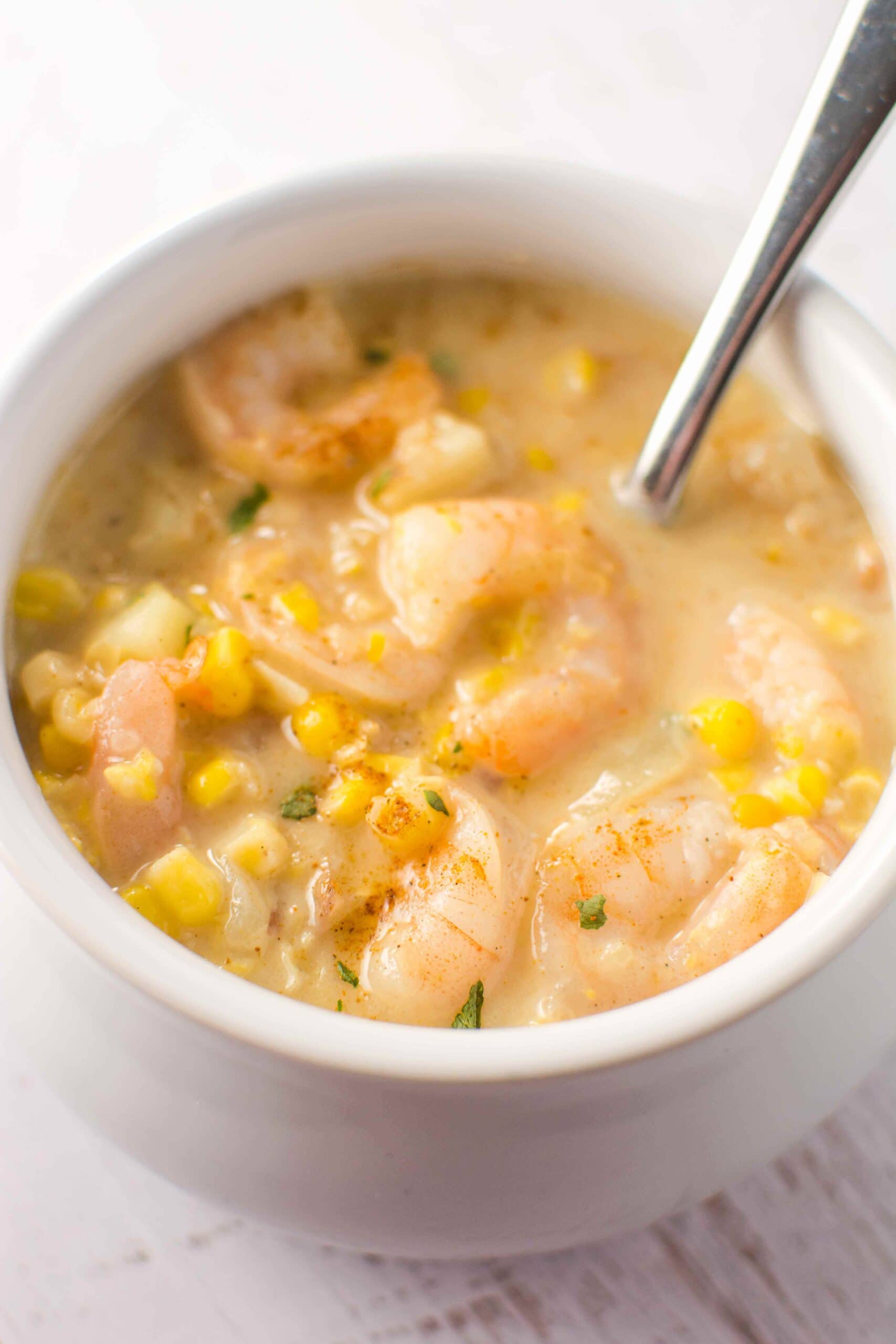 white bowl and spoon filled with cajun corn and shrimp chowder