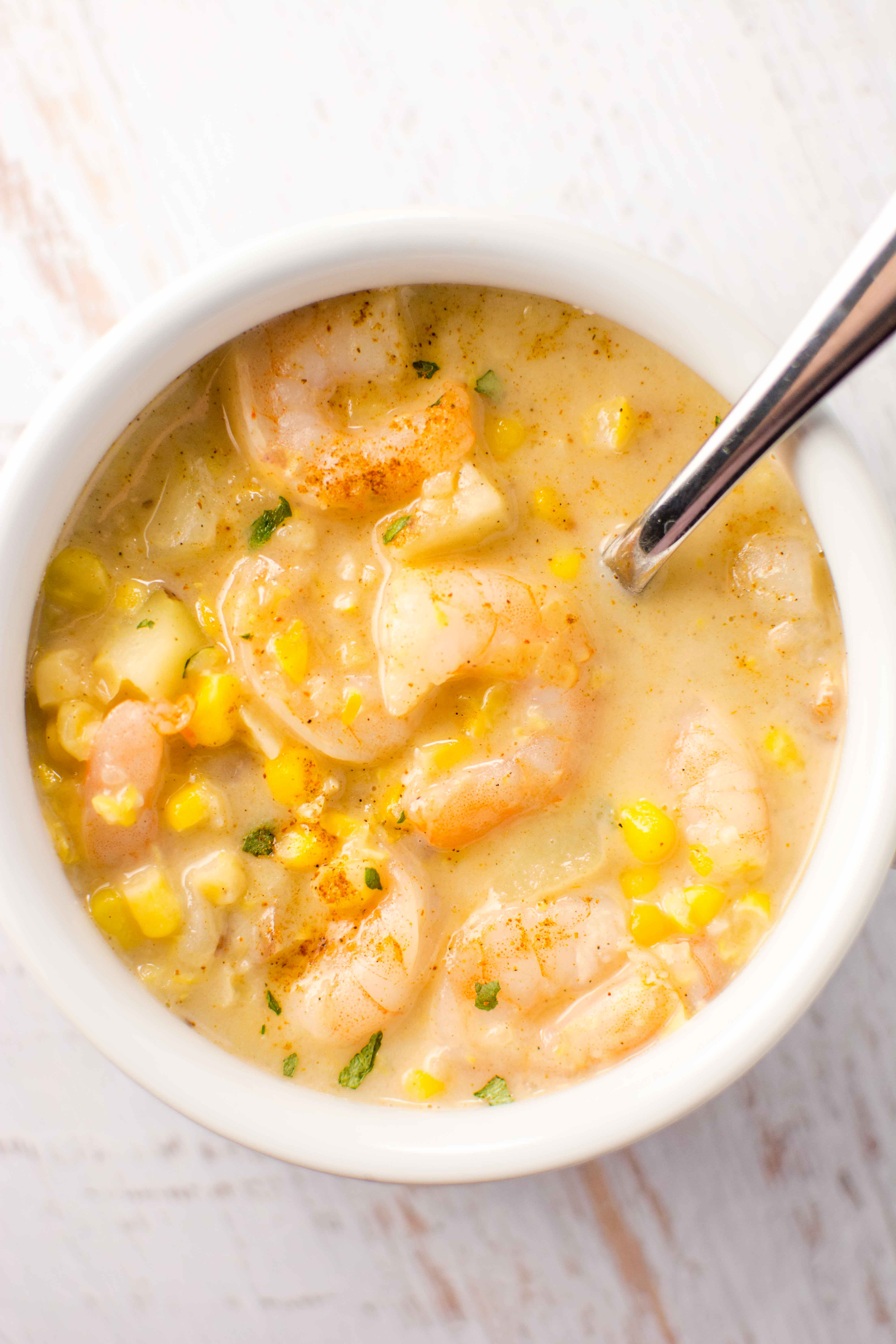white bowl and spoon filled with cajun corn and shrimp chowder