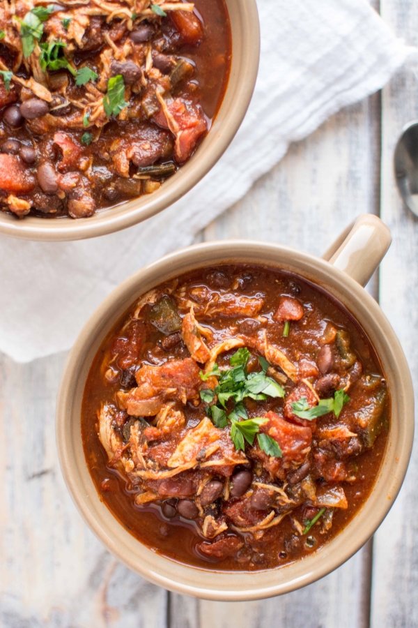 roasted tomato and ancho chicken chili in two tan serving bowls with handles