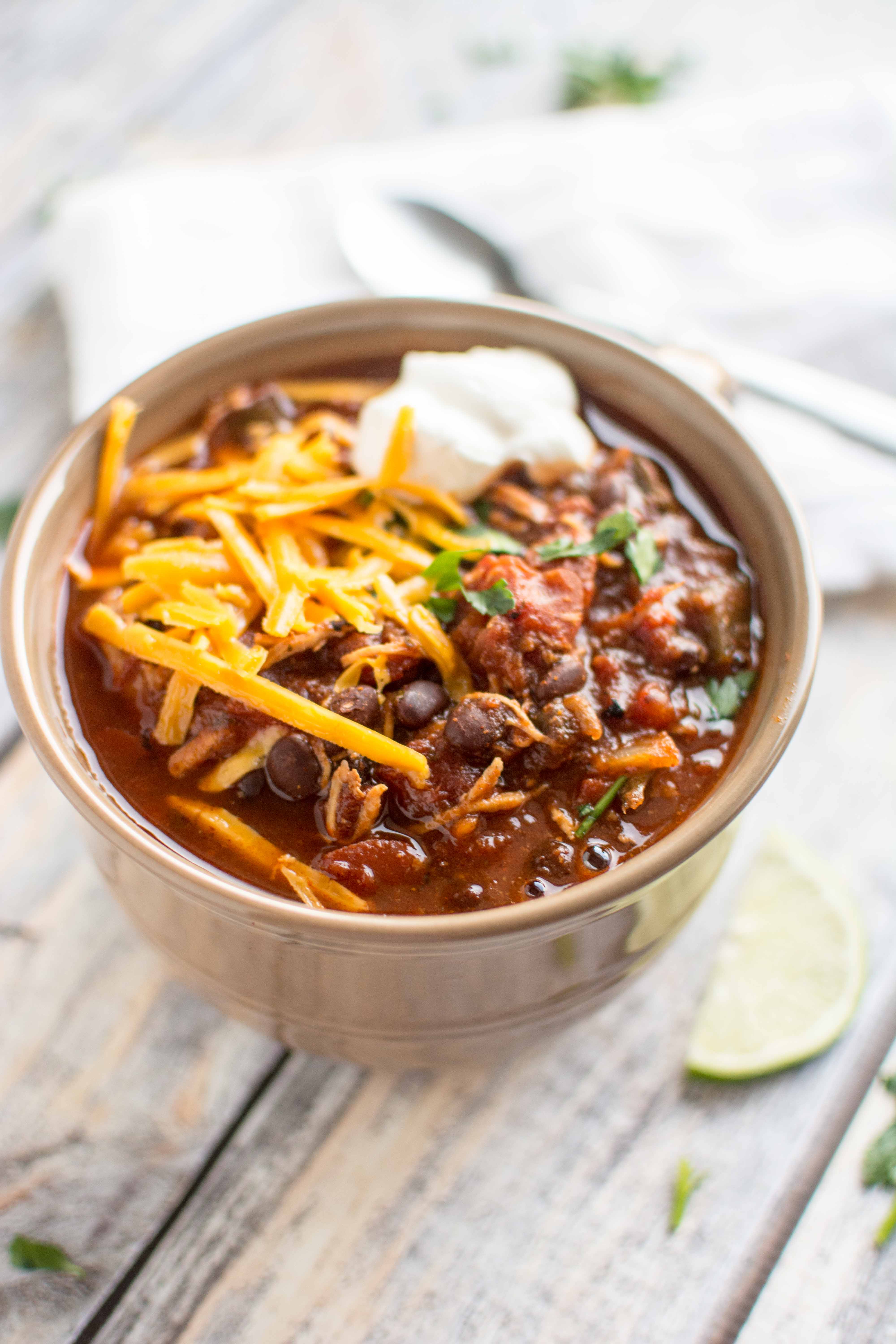 roasted tomato and ancho chicken chili in two serving bowl with cheese and sour cream