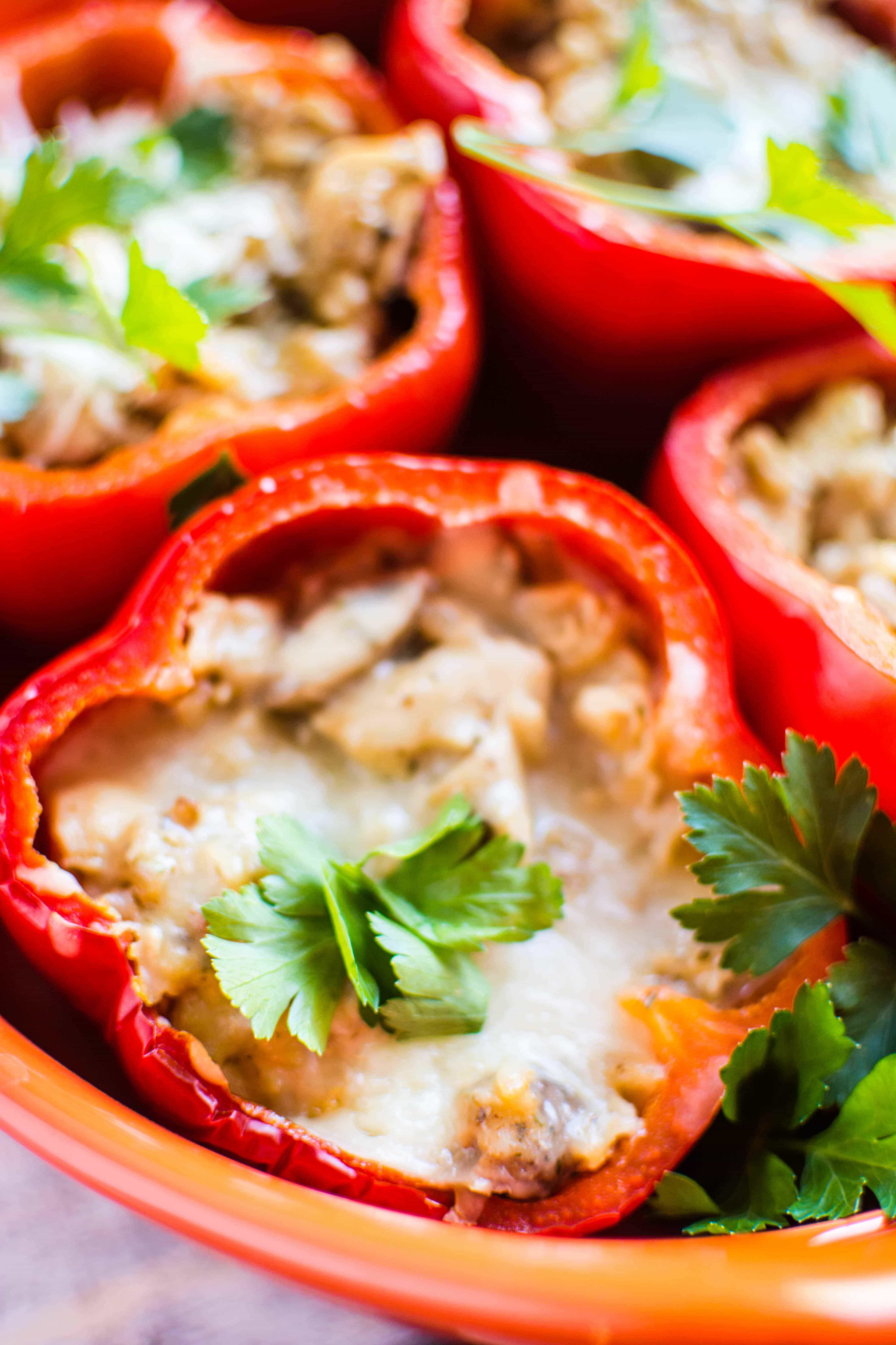four stuffed red peppers in red serving dish