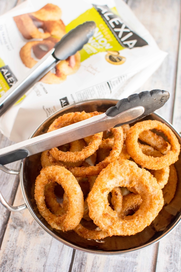 bowl of onion rings with tongs and bag of Alexia Onion Rings in background