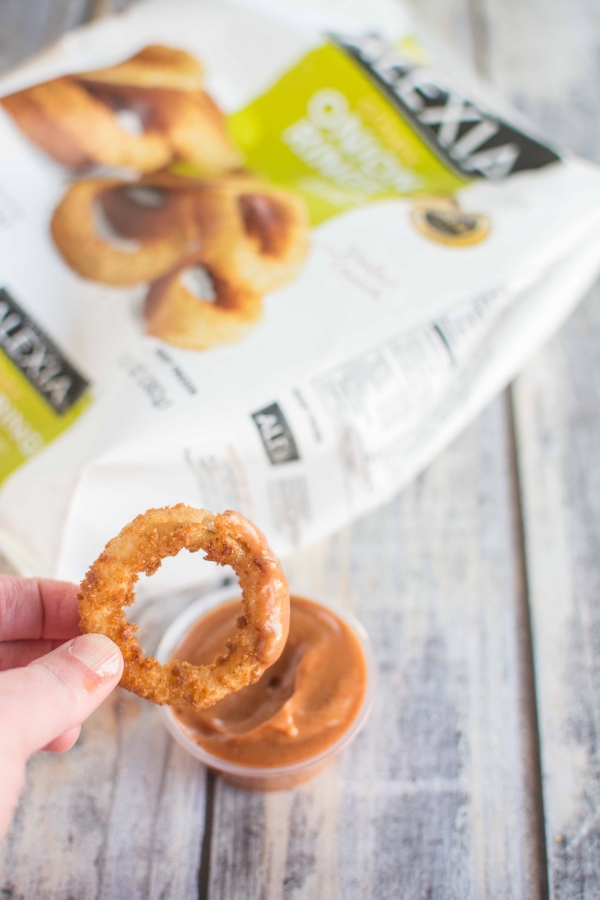 onion ring with dipping sauce with bag of Alexia Onion Rings in background