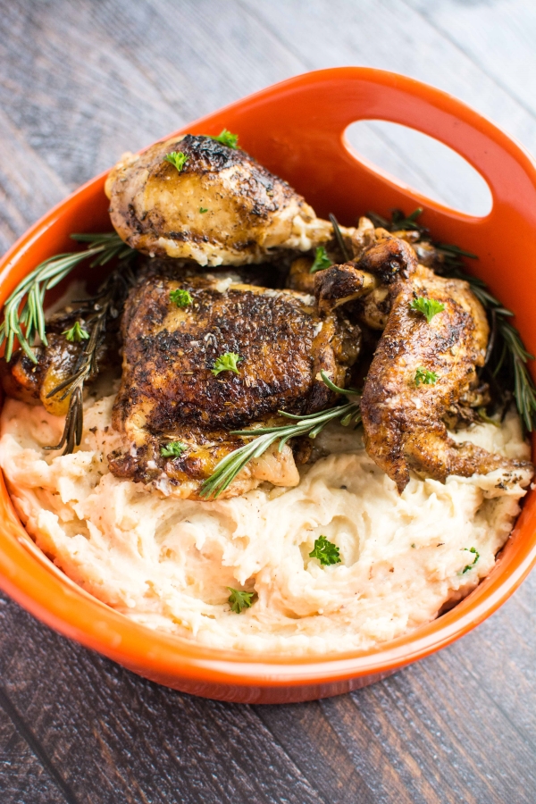 rosemary balsamic chicken and mashed potatoes in orange serving bowl with rosemary sprigs on top