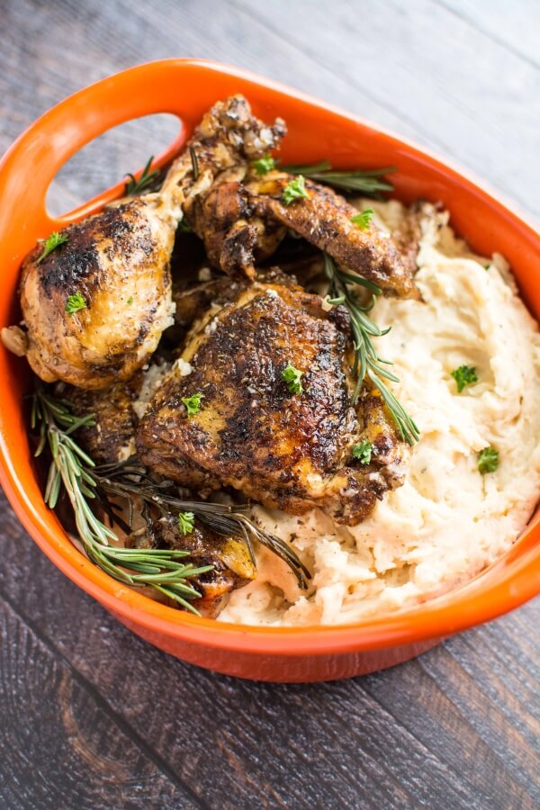 orange serving bowl filled with rosemary balsamic chicken with mashed potatoes on side