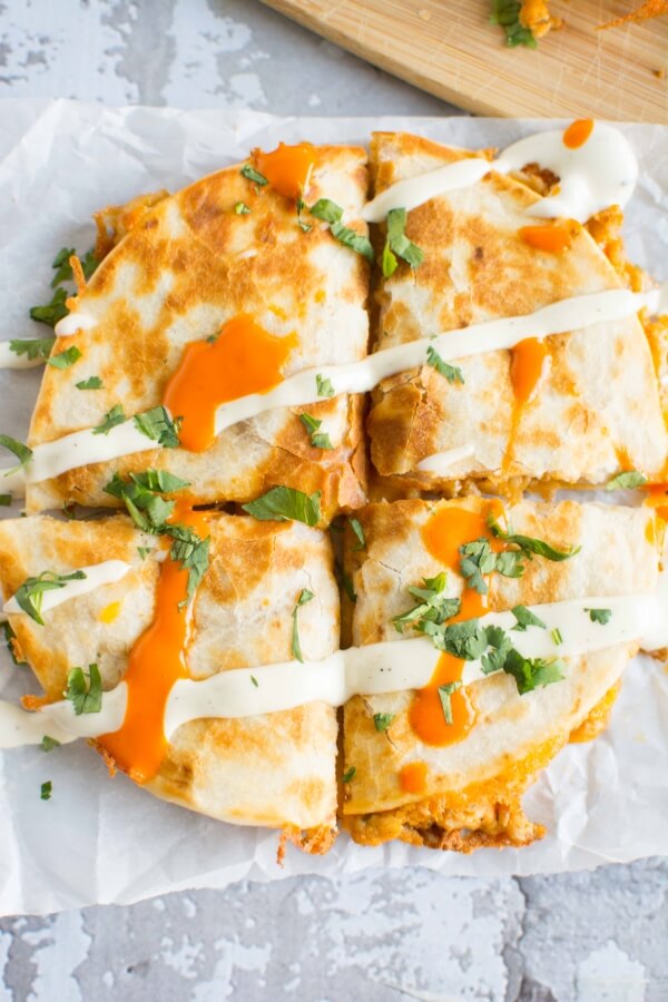 1 quesadilla cut in 4 pieces on parchment paper, drizzled with buffalo sauce and ranch dressing