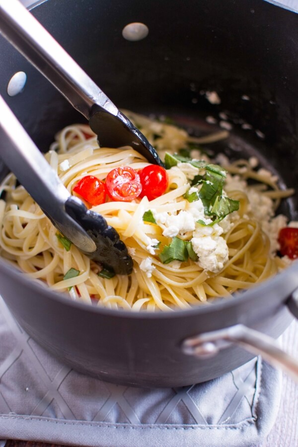 tomato basil and goat cheese pasta in pan, tossed with tongs