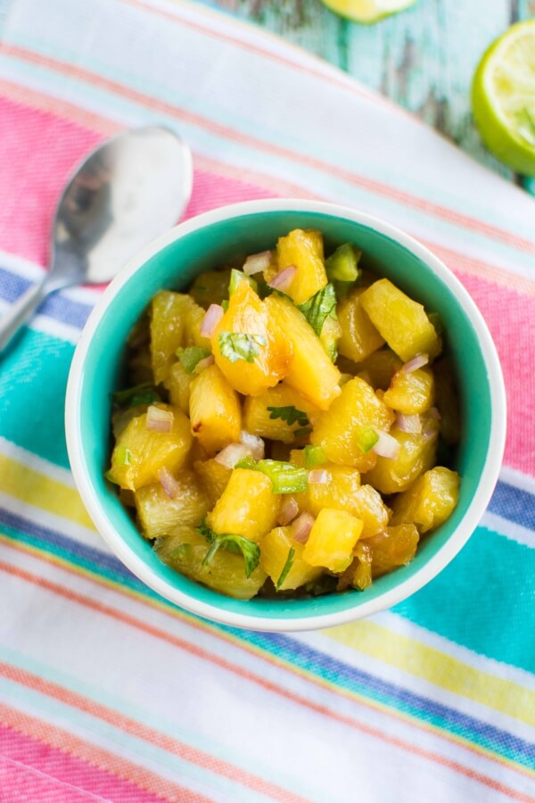 green bowl with pineapple salsa with spoon on side