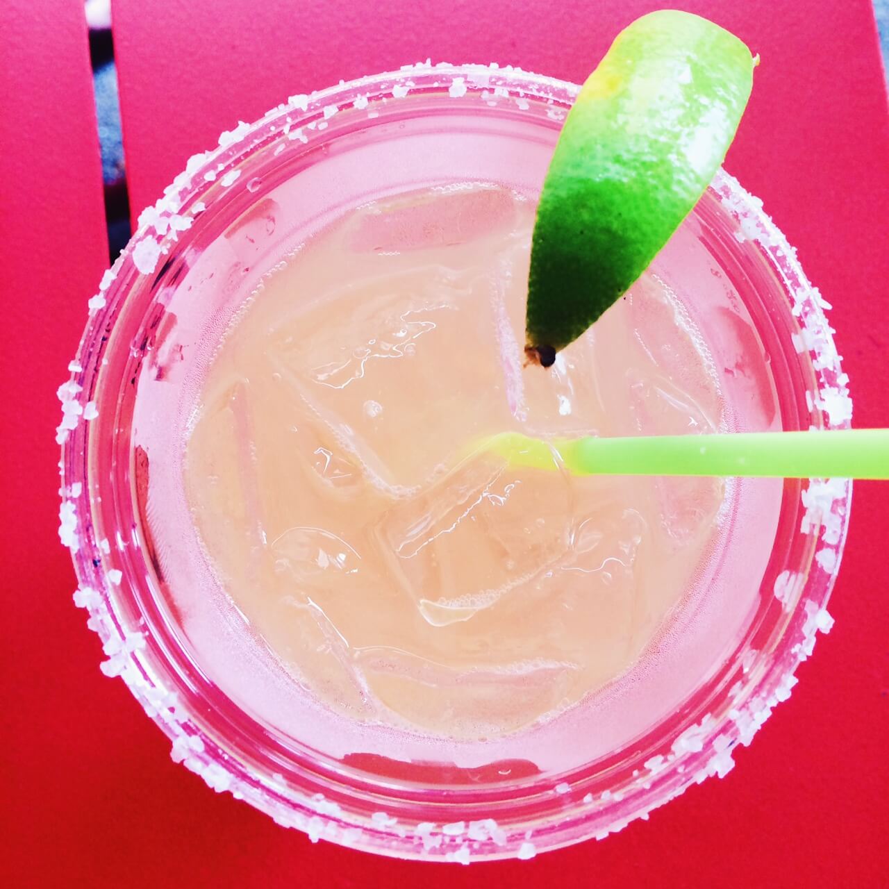 salt lined margarita glass with lime wedge and green straw