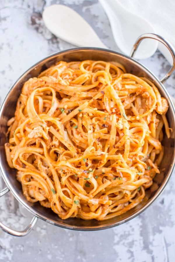 firecracker chicken pasta in bowl with white wooden spoon on side