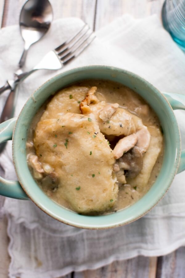 green bowl filled with Chicken Gravy and Biscuits with fork and spoon on side