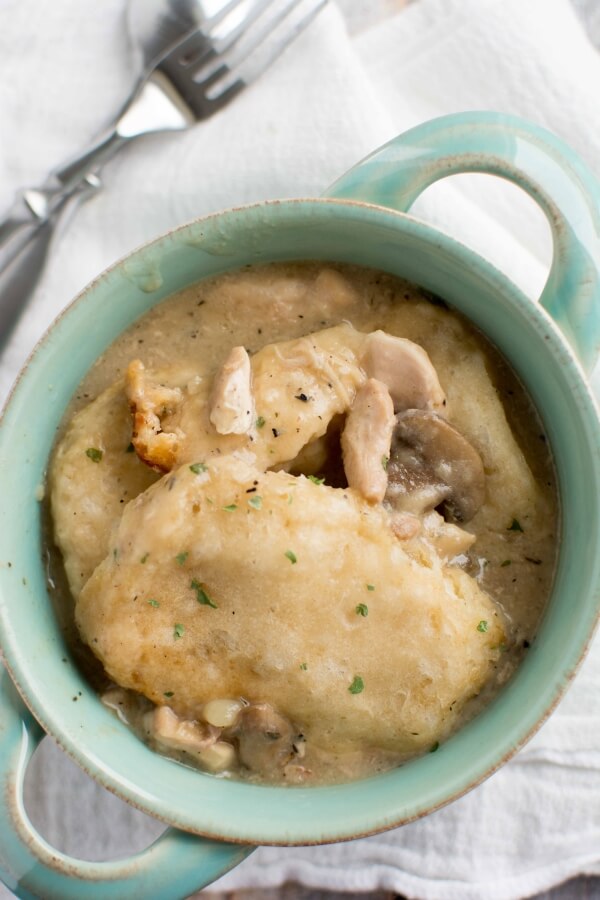 green bowl filled with Chicken Gravy and Biscuits with fork and spoon on side