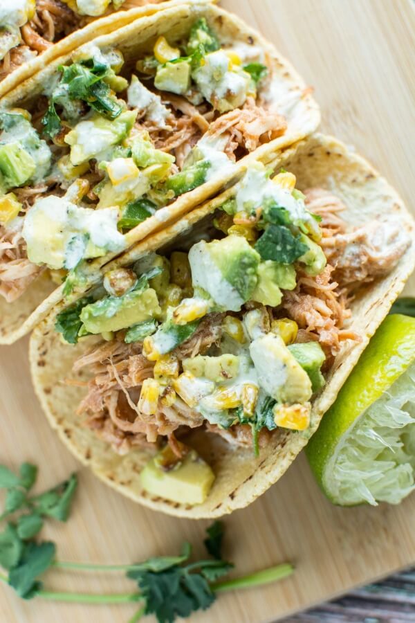 three Raspberry Chipotle Chicken Tacos on wooden cutting board with lime wedge