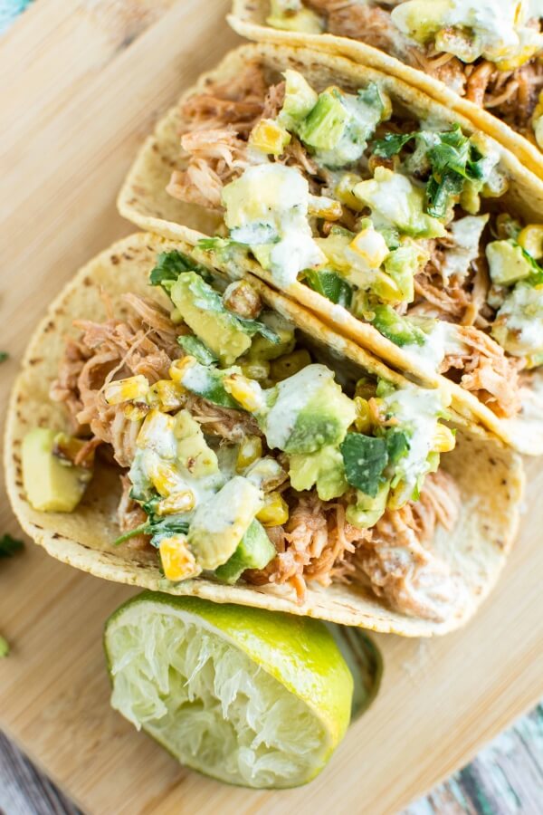 three Raspberry Chipotle Chicken Tacos on wooden cutting board with lime wedge