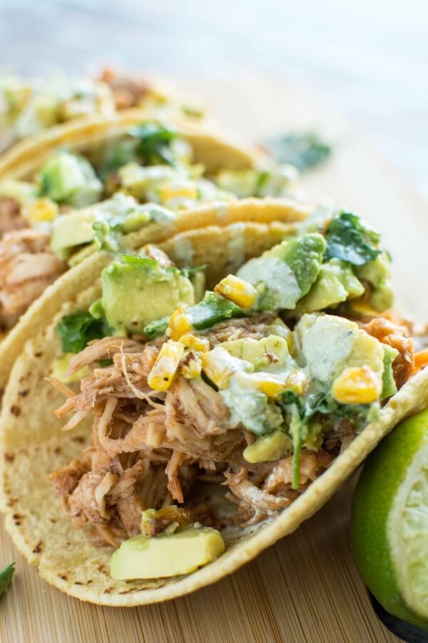 three Raspberry Chipotle Chicken Tacos on wooden cutting board with lime wedge