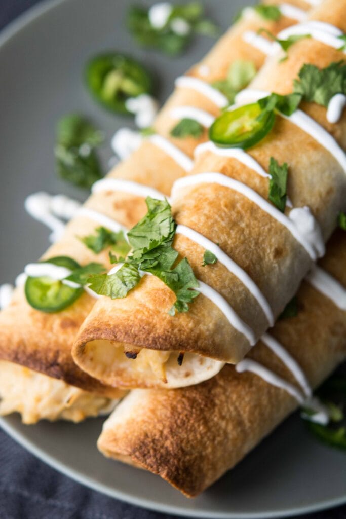 Up close picture of Slow Cooker Jalapeno Popper Chicken Flautas on a grey plate