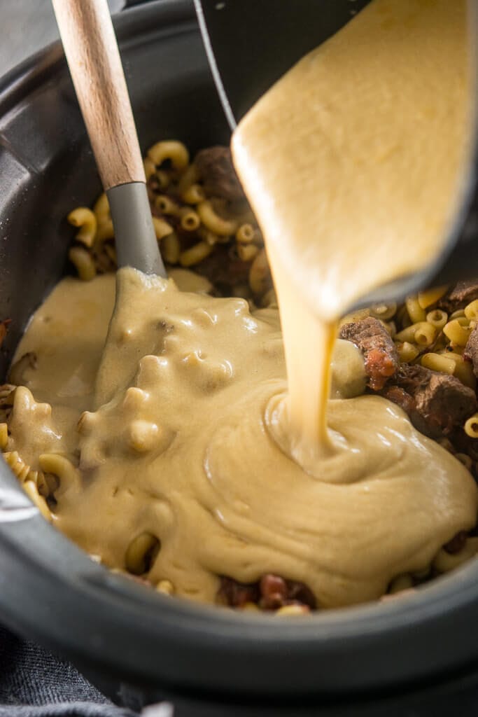 Pouring the cheese sauce into the noodles and beef to make Slow Cooker Beer Mac & Cheese