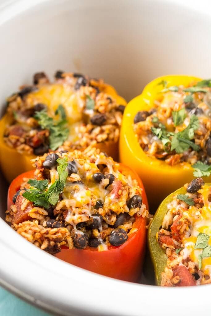 Close up picture of slow cooker stuffed peppers topped with cilantro in white crock. 