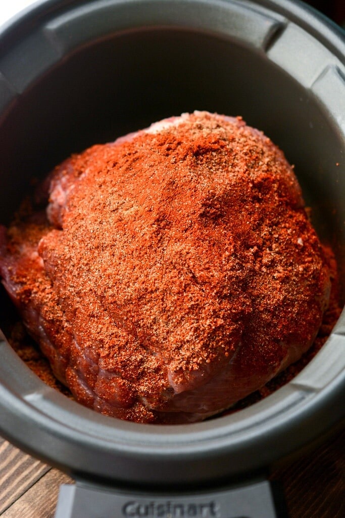 pork shoulder rubbed with spices in a slow cooker to make slow cooker pulled pork