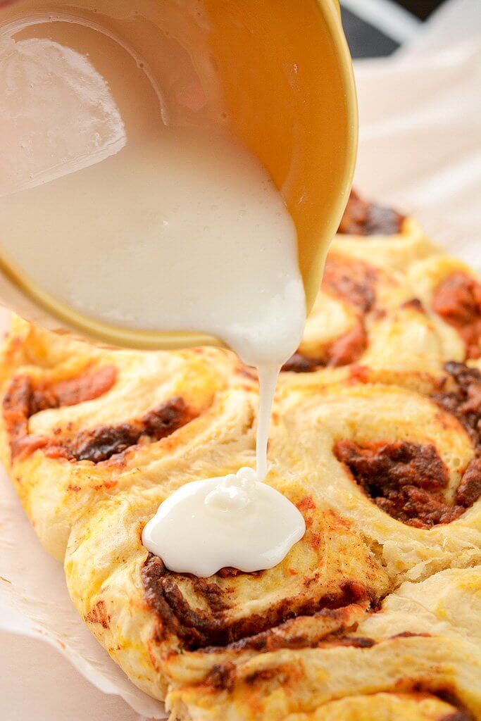 Pouring Icing Over Rolls - Slow Cooker Pumpkin Cinnamon Rolls