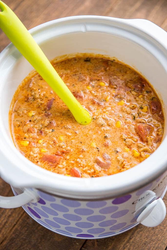 top view of buffalo chicken chili in purple dot slow cooker with yellow spoon