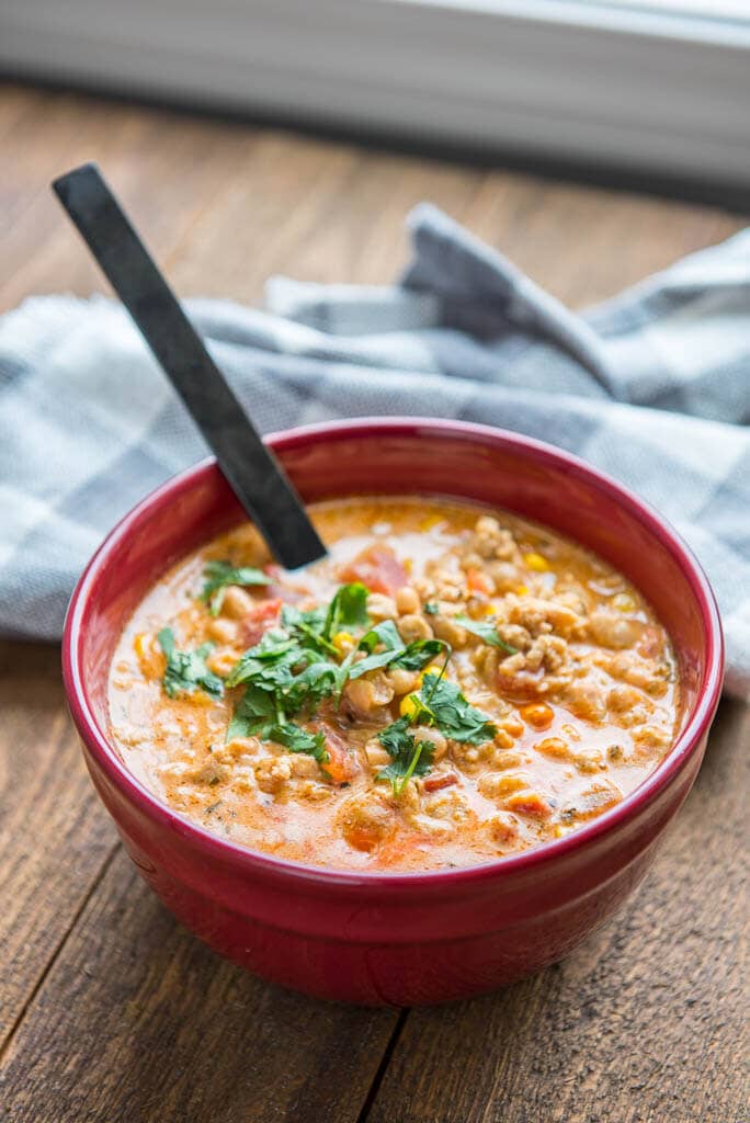 buffalo chicken chili in red bowl with black spoon