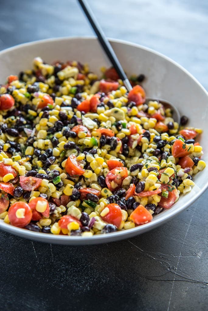 Black Bean and Corn Salsa in a large white bowl with a black spoon
