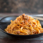 Veggie Packed Instant Pot Spaghetti with Meat Sauce on a black plate with steam