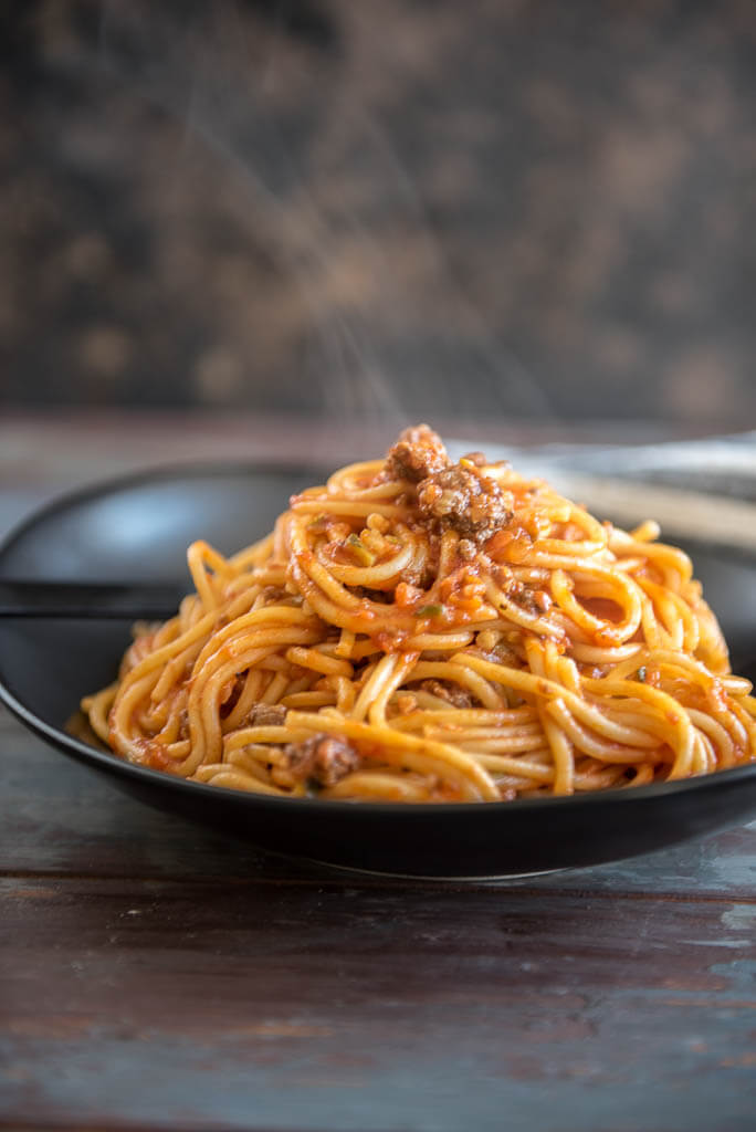 Veggie Packed Instant Pot Spaghetti with Meat Sauce on a black plate with steam