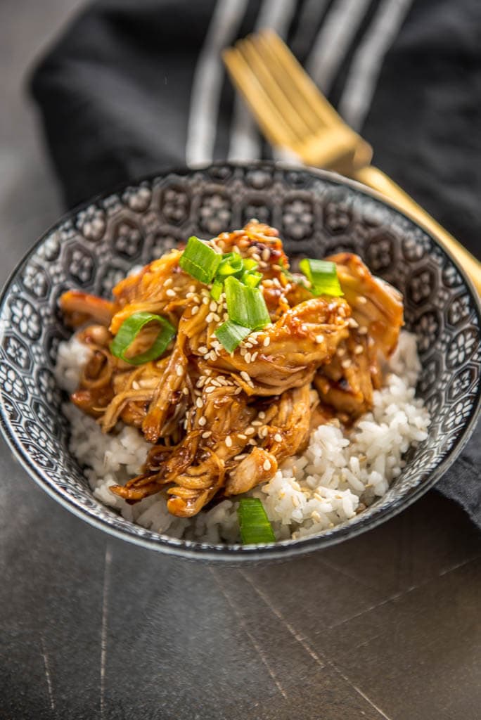 Slow Cooker Teriyaki Chicken in black and white bowls topped with green onion