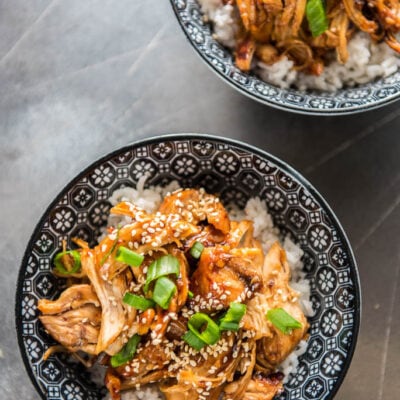 Slow Cooker Teriyaki Chicken in black and white bowls topped with green onion