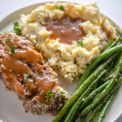 slow cooker meatloaf with buttermilk mashed potatoes and green beans on white plate