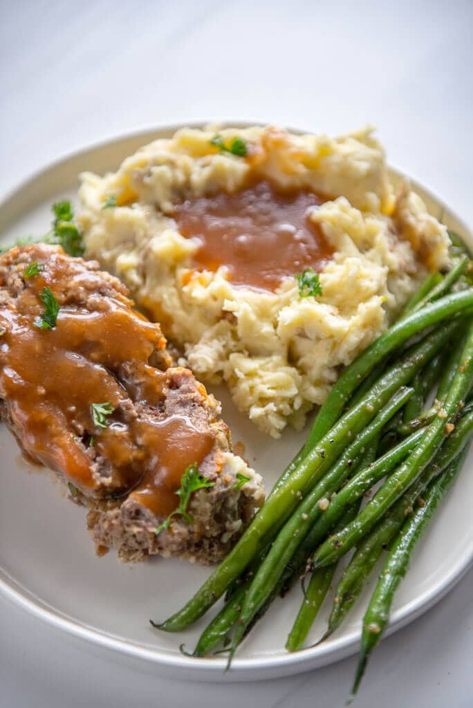 slow cooker meatloaf with buttermilk mashed potatoes and green beans on white plate