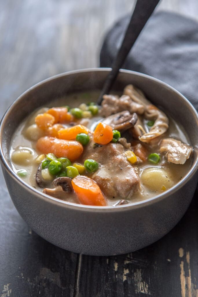 instant pot chicken and dumplings with veggies in gray bowl with black spoon