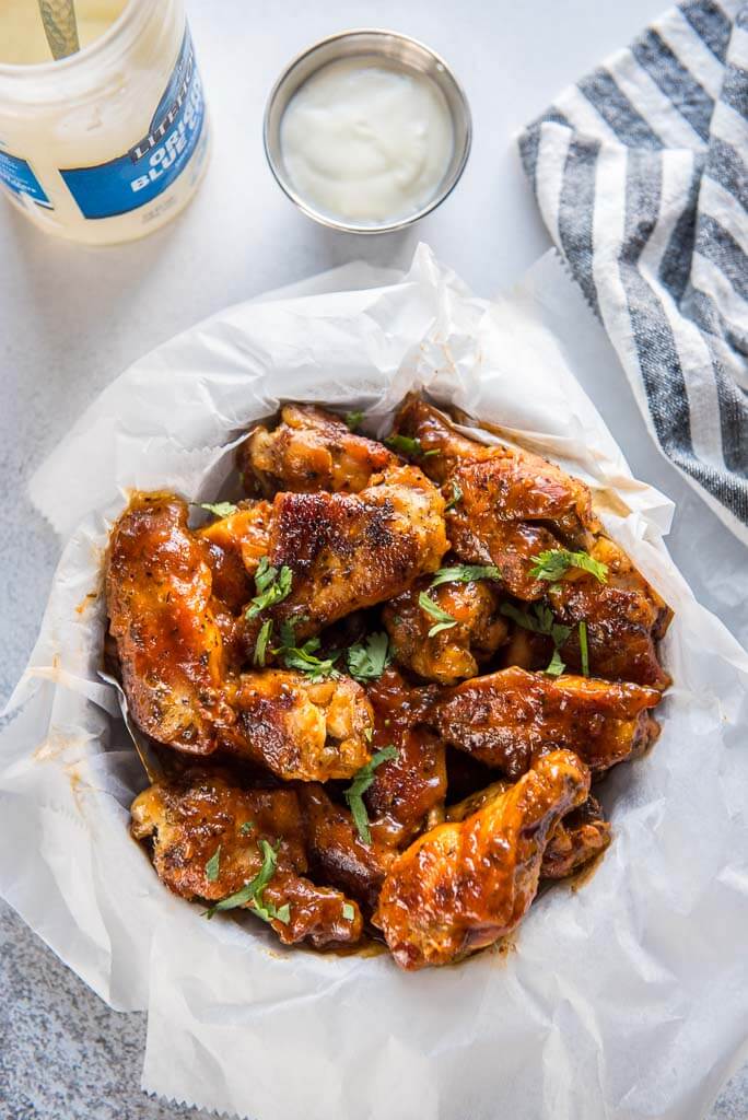 bowl filled with slow cooker chicken wings with honey buffalo sauce with a side of blue cheese dressing