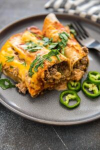slow cooker enchiladas on gray plate with sliced jalapeños
