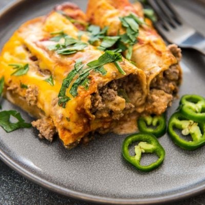 slow cooker enchiladas on gray plate with sliced jalapeños