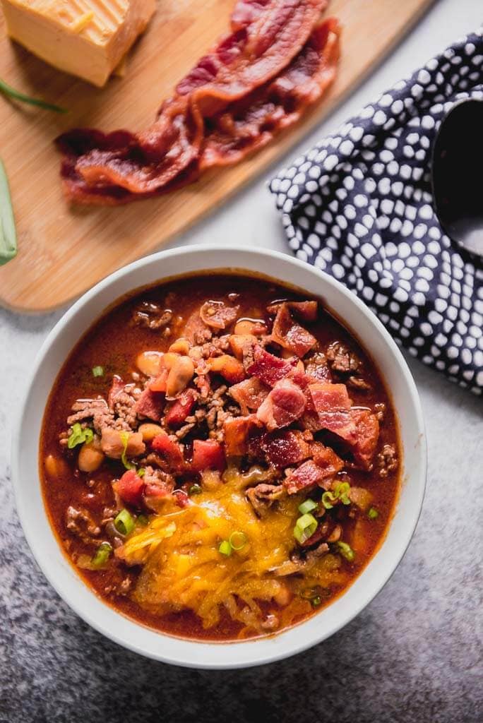slow cooker maple bacon chili topped with cheese and green onions