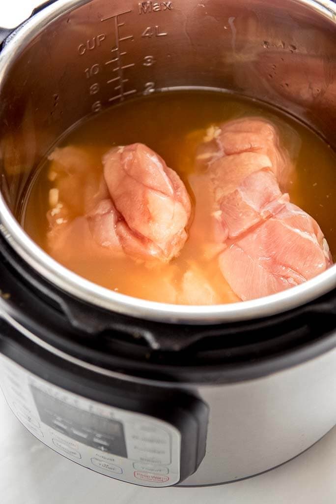 raw chicken breasts with chicken broth in