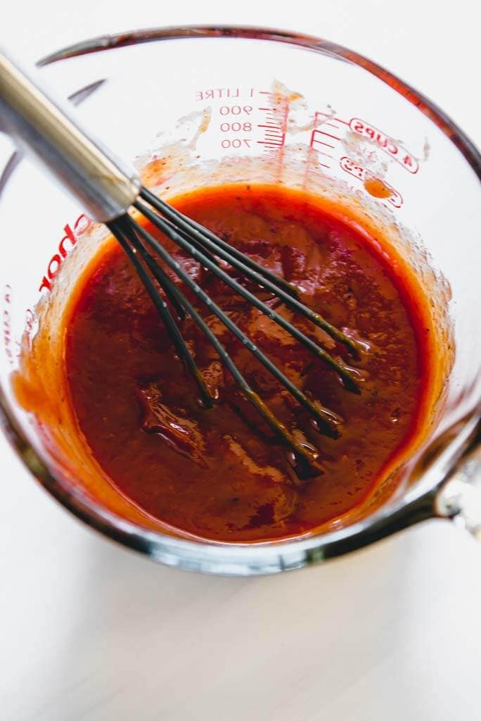 measuring cup with sauce mixture and whisk