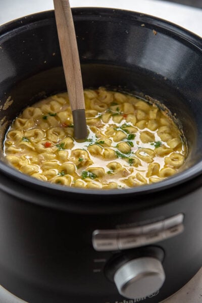 chicken tortellini soup in slow cooker with ladle
