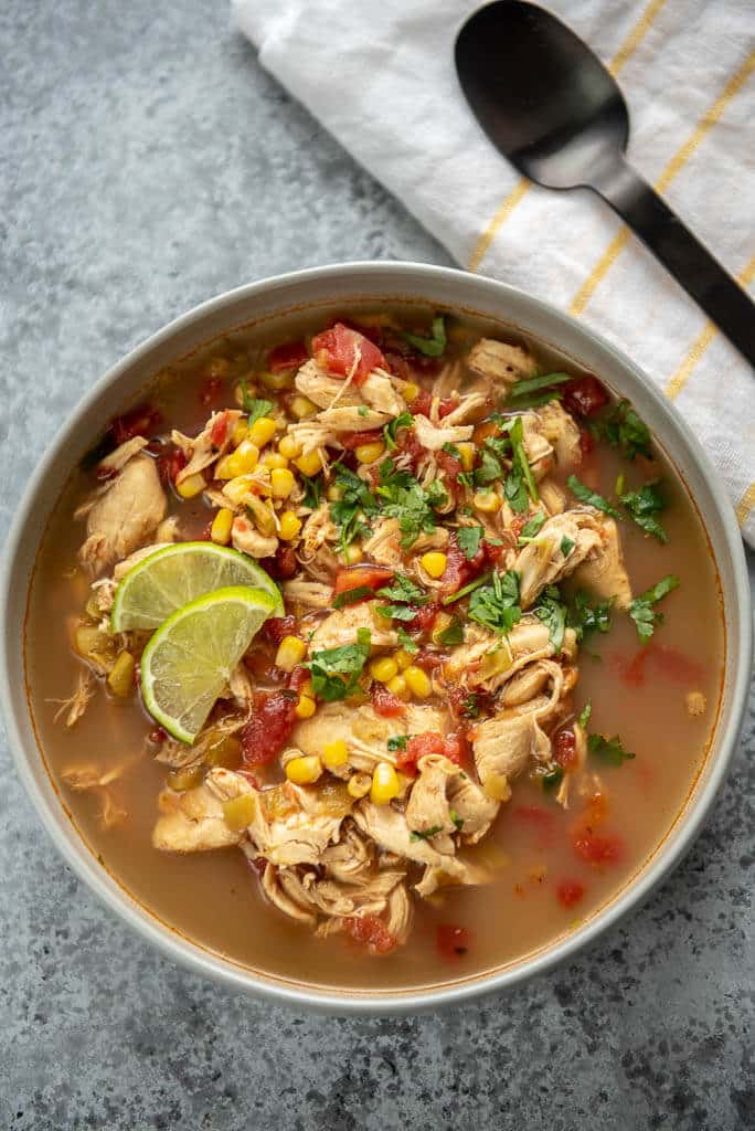 gray bowl full of spicy chicken soup topped with cilantro