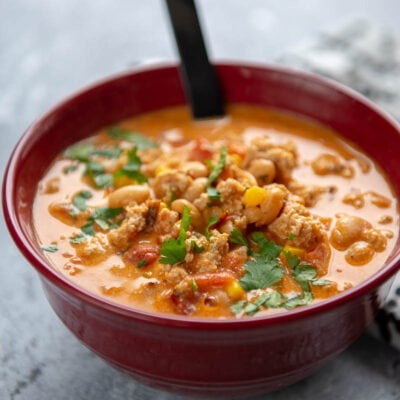 buffalo chicken in a red bowl with a black spoon