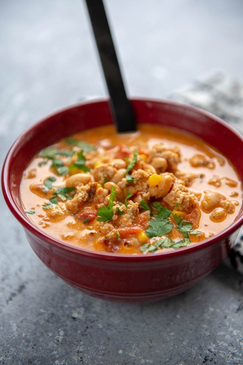 buffalo chicken in a red bowl with a black spoon