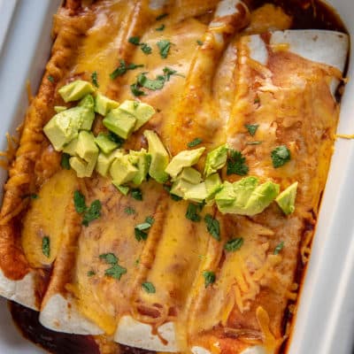 butternut squash enchiladas topped with avocado in a casserole slow cooker