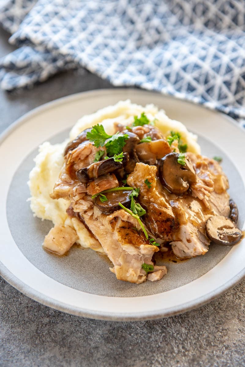 pork roast with mashed potatoes and mushroom gravy on gray plate